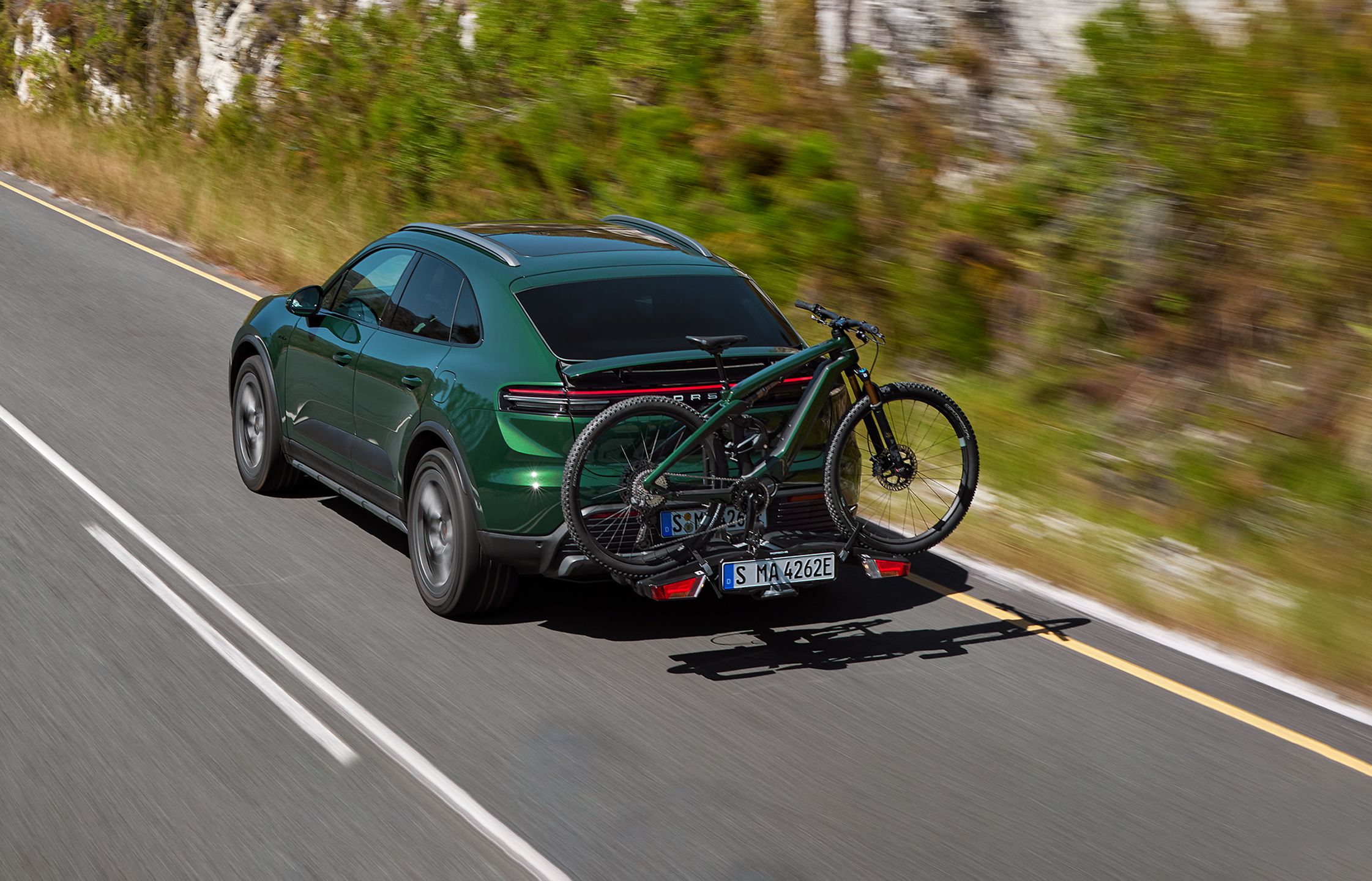Shows Picture of oakgreen_Porsche_Macan_with_an_oakgreen_Porsche_eBike_driving_on_a_rack.png