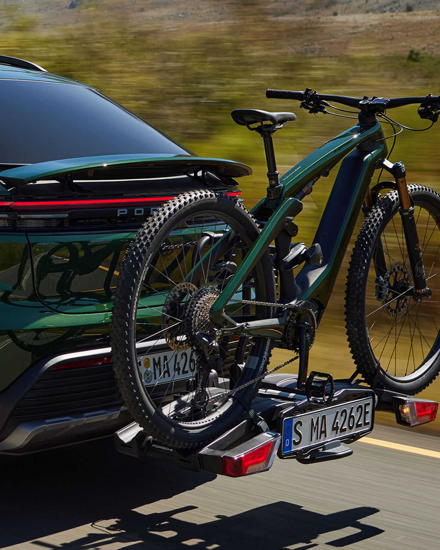 Shows Picture of oakgreen_Porsche_Macan_with_an_oakgreen_Porsche_eBike_on_a_rack.png